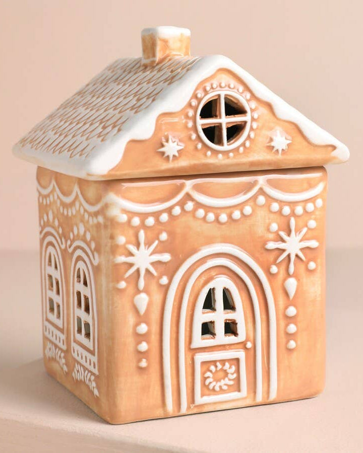 Decorative gingerbread house-shaped container on a beige background