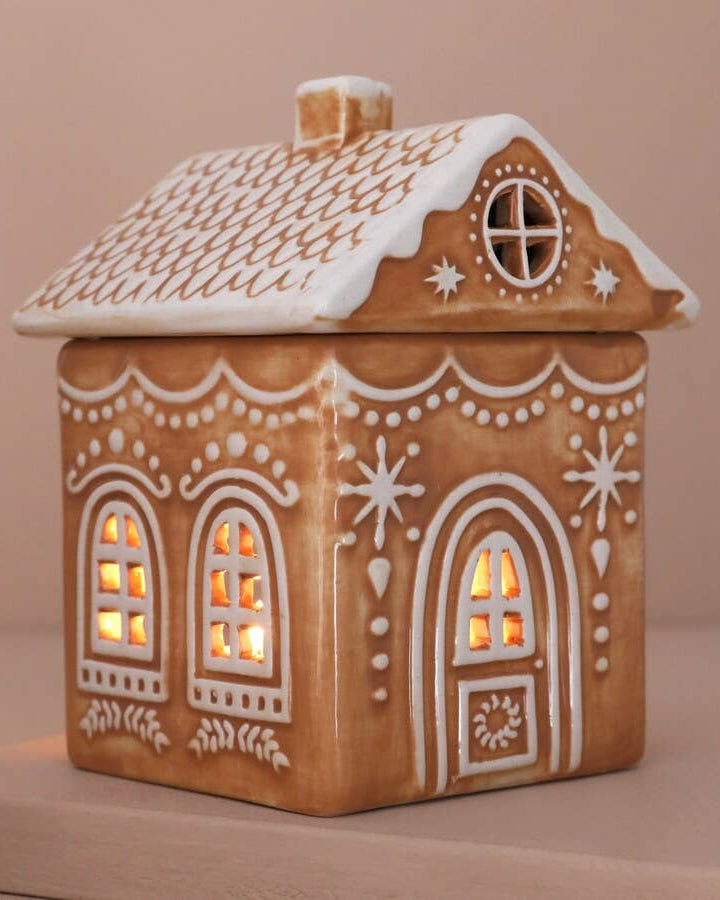 Ceramic house-shaped lantern with decorative details on a beige background