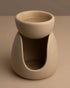 Beige ceramic wax melt burner on a neutral table and background