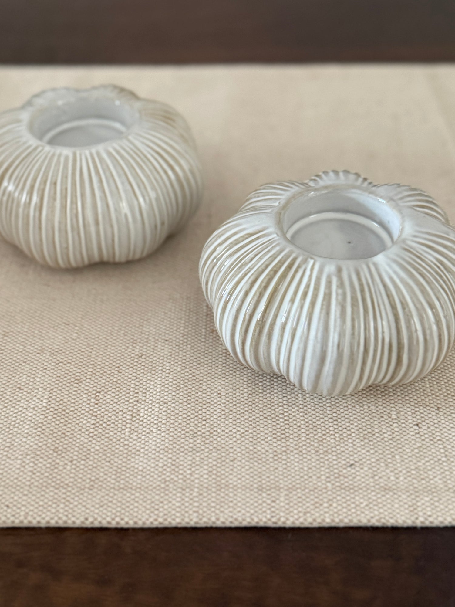 Two ribbed ceramic candle holders on a textured surface