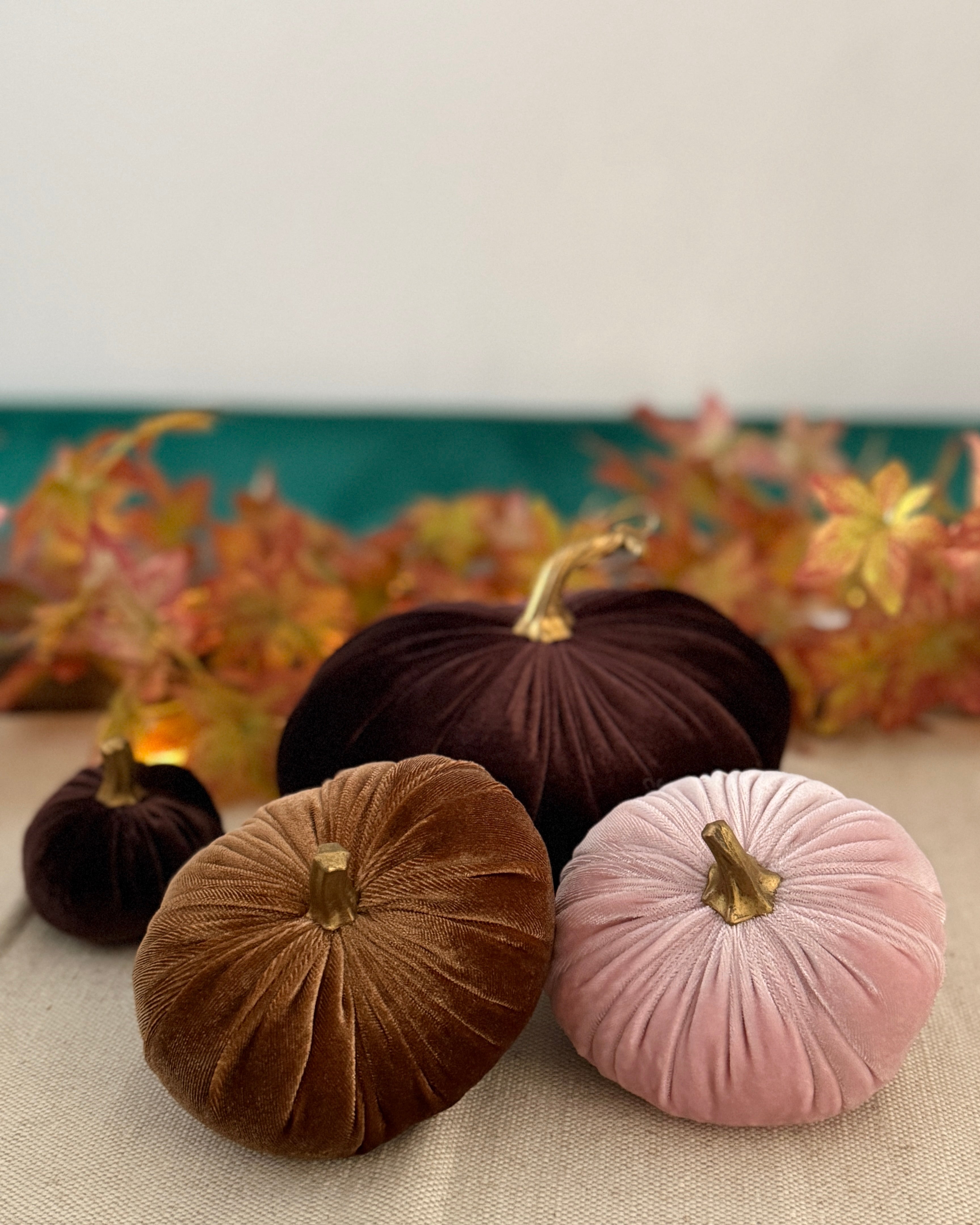 Decorative pumpkins in brown and pink on a table with a floral background
