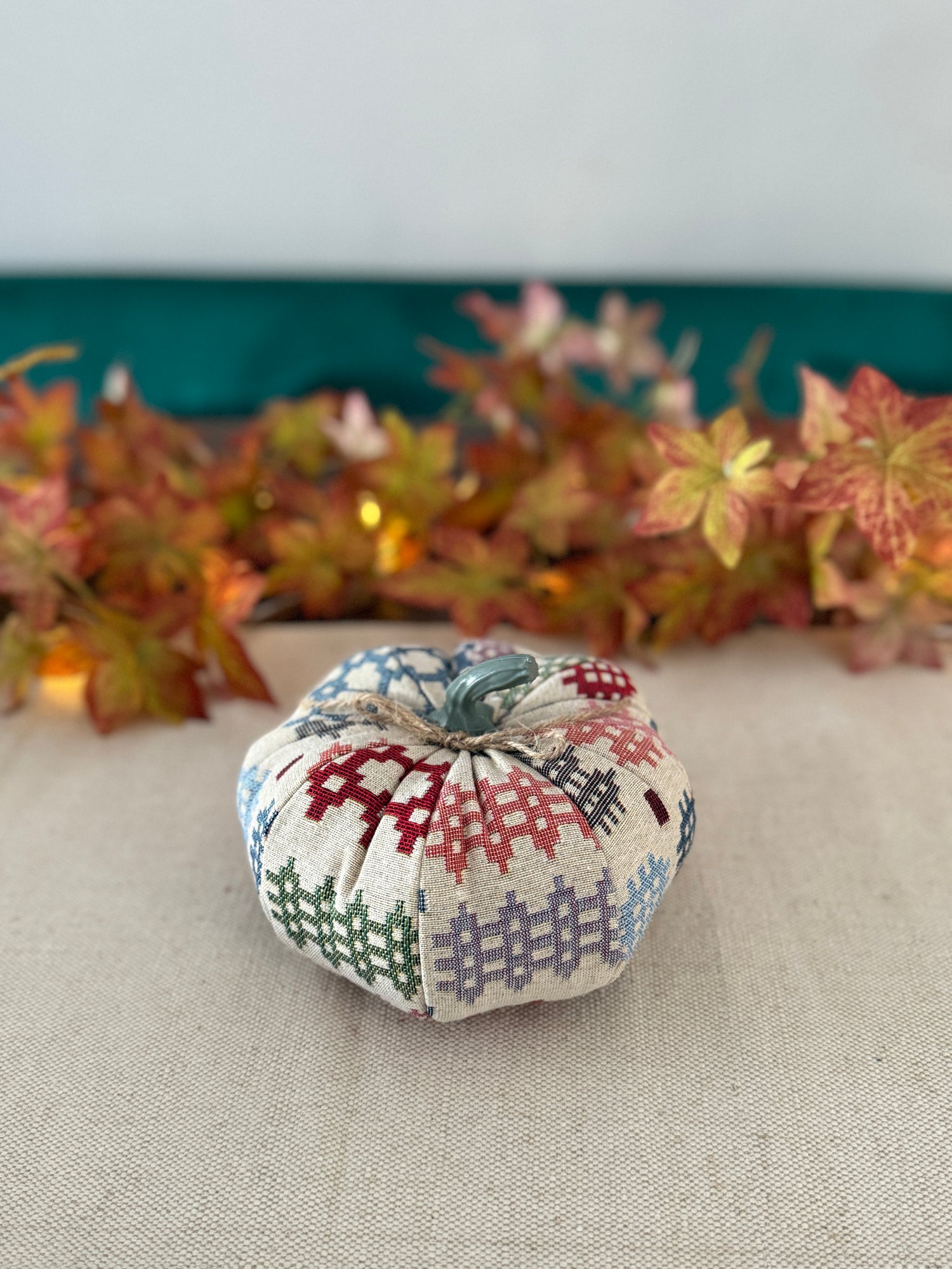 Decorative fabric pumpkin with a patchwork pattern on a neutral background