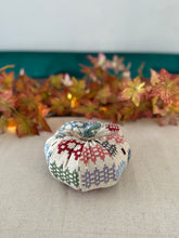 Decorative fabric pumpkin with a patchwork pattern on a neutral background
