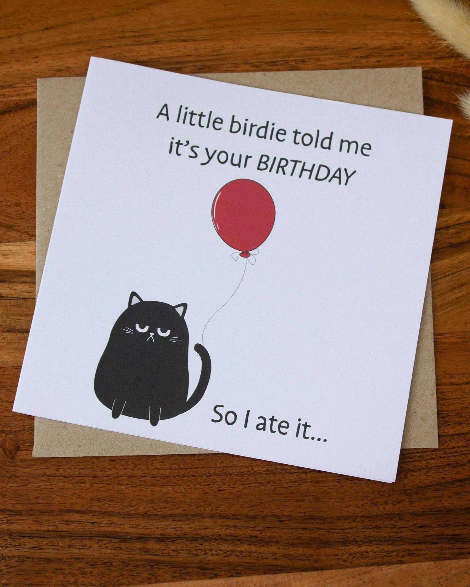 Square birthday card with a humorous black cat illustration holding a red balloon and text: "A little birdie told me it’s your birthday, so I ate it." Made with sustainable materials.