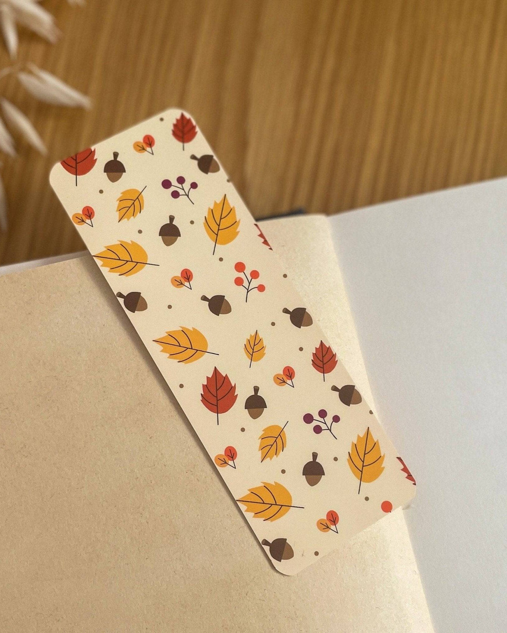 Autumn-themed waterproof bookmark featuring vibrant leaves in autumn colours, made from recycled tear-proof card stock with a velvet lamination. Perfect for book lovers.