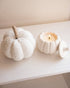 Two white pumpkins with a candle on a light surface