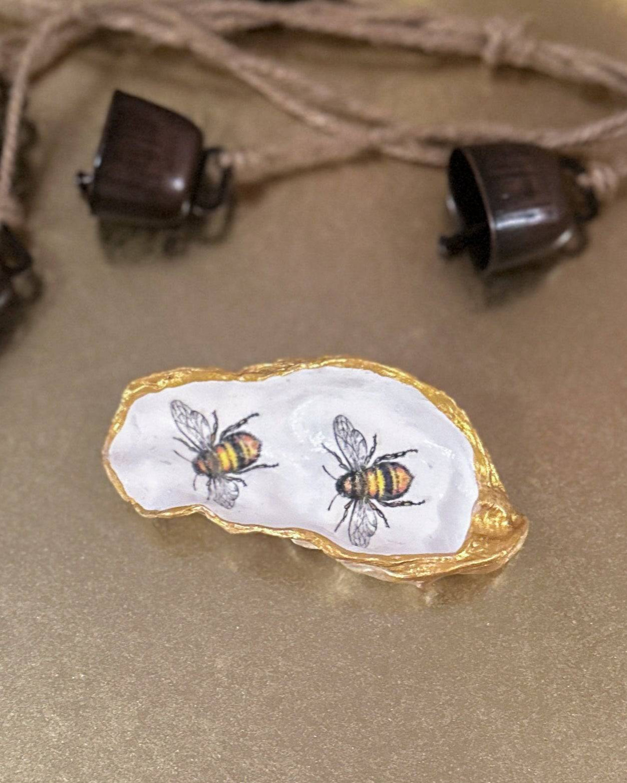 Handmade oyster shell trinket dish featuring two bumble bees, crafted using a meticulous decoupage technique with hand-painted gold edges, perfect for spring jewellery storage or home decor.
