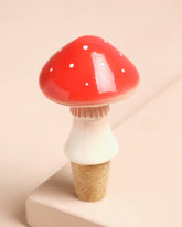 Mushroom-shaped bottle stopper with red cap and white body on a beige background