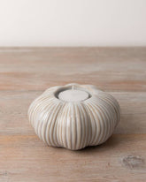 Set of two ceramic pumpkin tea light holders featuring intricate ribbing and a warm cream colour. Ideal for autumn décor.