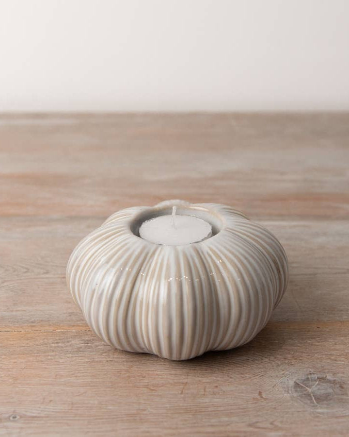 Set of two ceramic pumpkin tea light holders featuring intricate ribbing and a warm cream colour. Ideal for autumn décor.