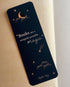 Dreamy waterproof bookmark featuring a night sky illustration with a person reading on the moon, stars, clouds, and denim blue and gold accents. Made in the UK with recycled, tear-proof card stock.