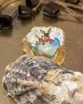 Handmade oyster shell trinket dish featuring an Easter bunny and open egg shell illustration, crafted with a decoupage technique and hand-painted gold edges, perfect for Easter or springtime gifts.