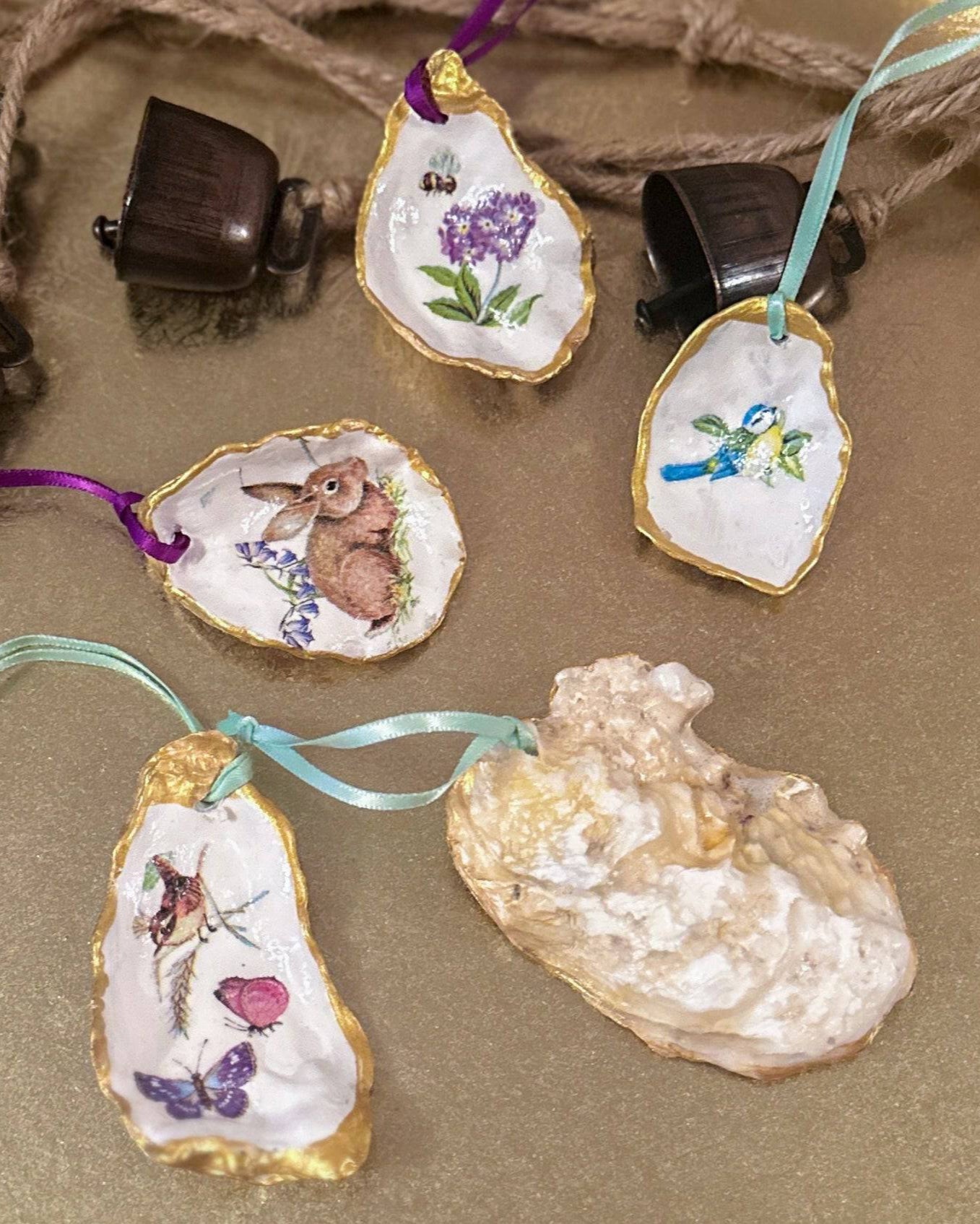 Set of five handmade Easter hanging ornaments crafted from oyster shells, various sizes, featuring a decoupage technique with hand-painted gold edges, decorated with spring motifs like bunnies, flowers, and bees, perfect for Easter or spring decor.