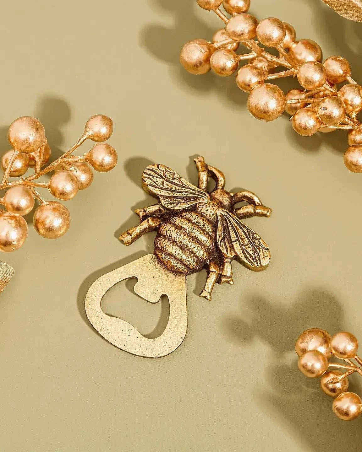 Gold bee-shaped bottle opener with floral elements on a beige background