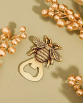 Gold bee-shaped bottle opener with floral elements on a beige background