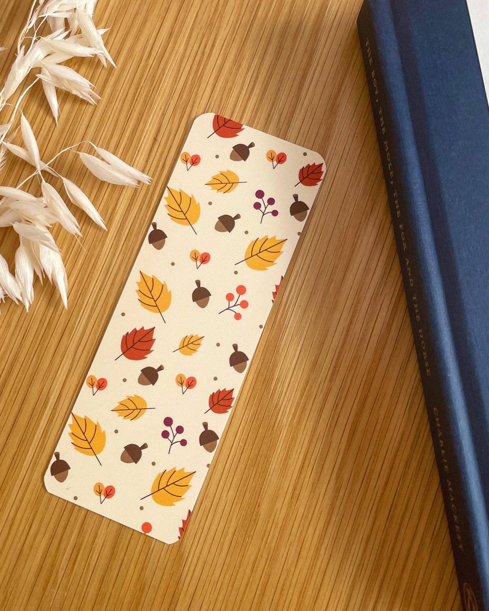 Autumn-themed waterproof bookmark featuring vibrant leaves in autumn colours, made from recycled tear-proof card stock with a velvet lamination. Perfect for book lovers.