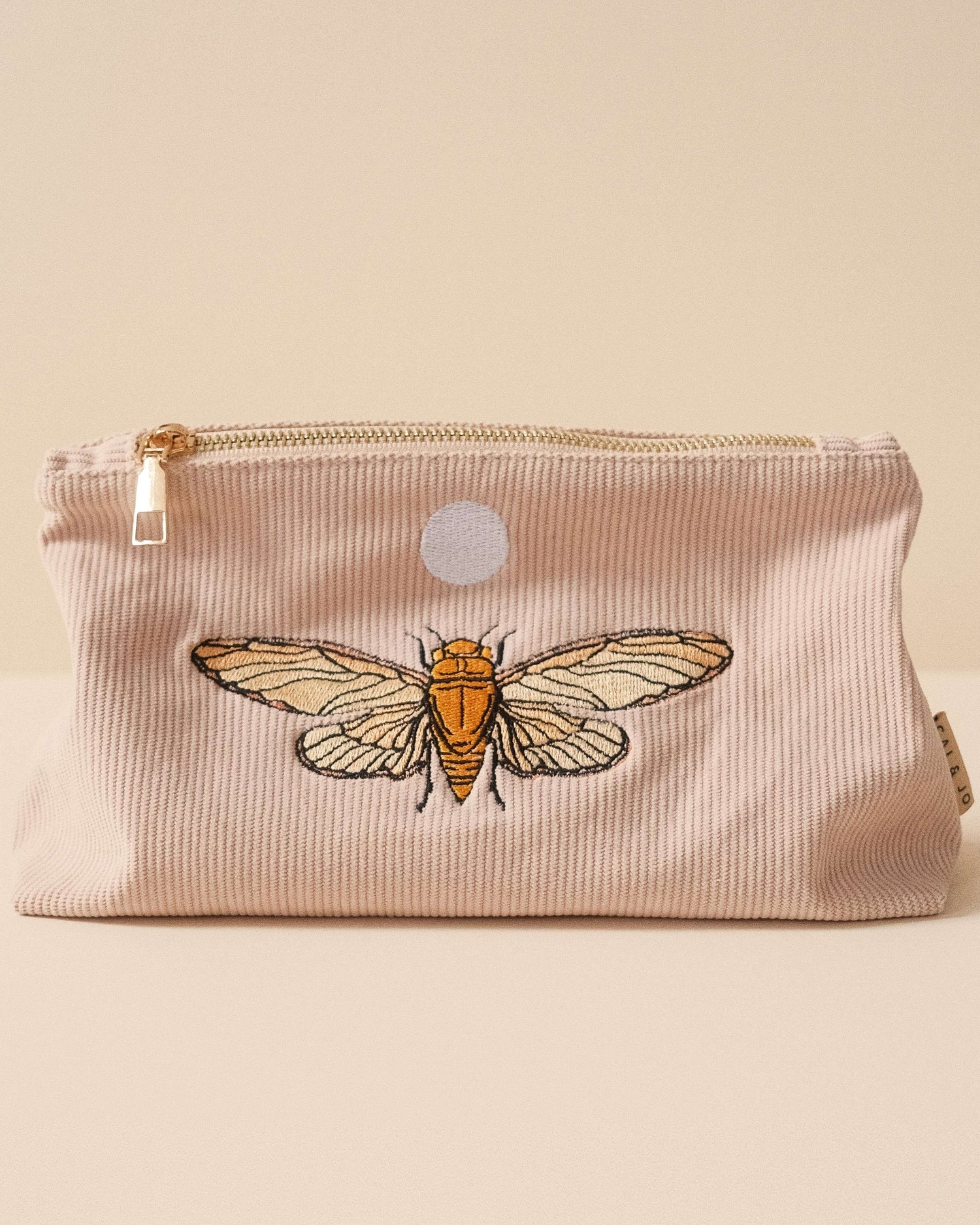 Medium pale pink corduroy pouch with a zip closure and embroidered designs of butterflies and flying insects. Fully lined for storing makeup, toiletries, or travel essentials.