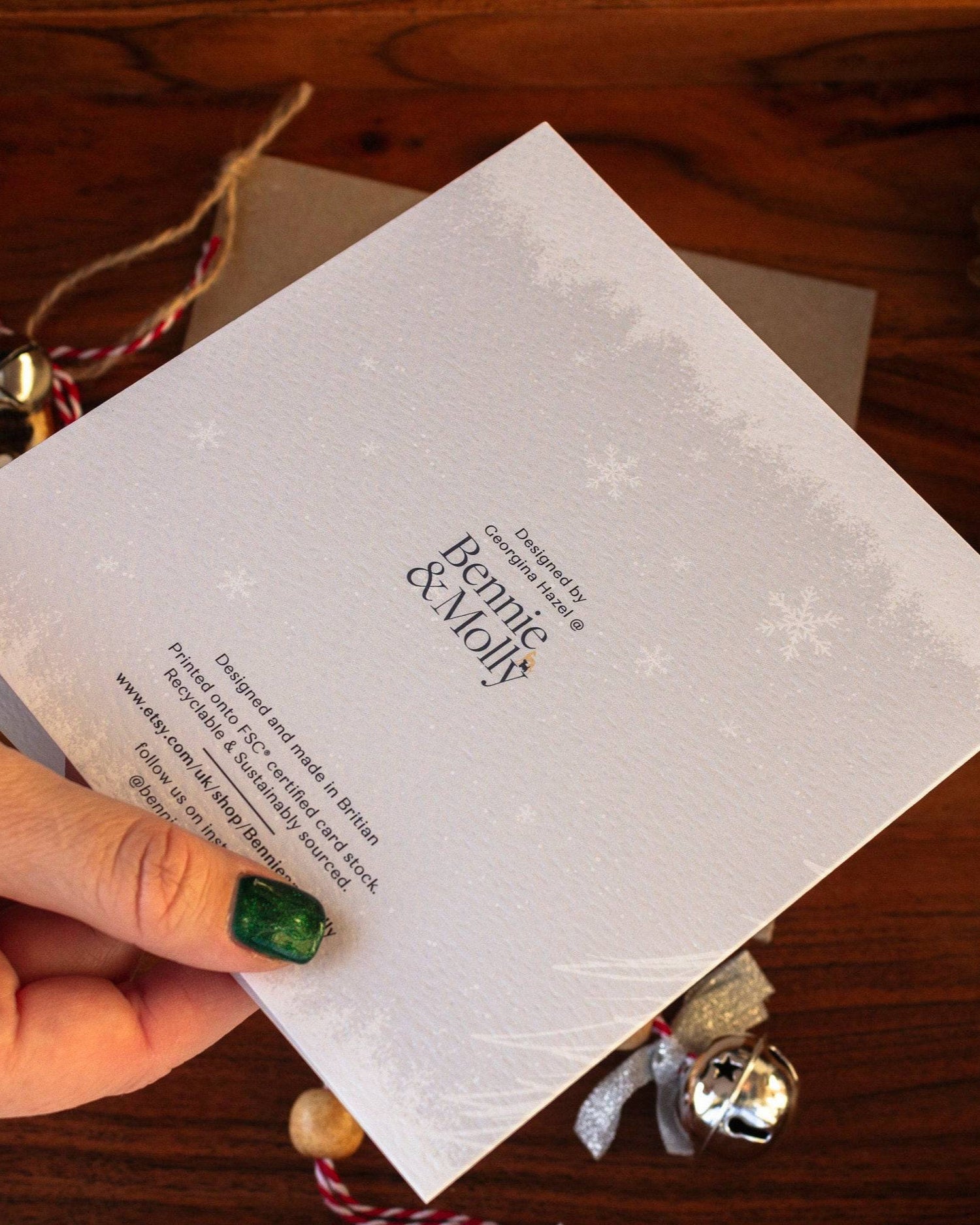 Square handmade Christmas card featuring a minimalist reindeer design in pale blue-grey tones with snow and trees, made with sustainably sourced textured paper and eco-friendly packaging.