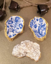 Set of three handmade oyster shell trinket dishes with blue and white floral designs, featuring a decoupage technique and hand-painted gold edges, ideal for home decor or jewellery storage.