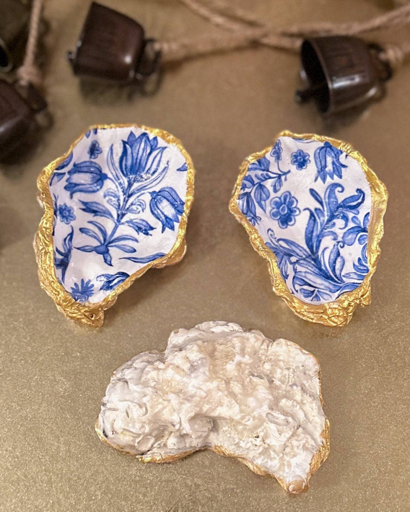 Set of three handmade oyster shell trinket dishes with blue and white floral designs, featuring a decoupage technique and hand-painted gold edges, ideal for home decor or jewellery storage.