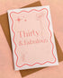 A6 handmade 30th birthday card featuring the words "Thirty & Fabulous" in pastel and bright pinks, with illustrations of a bow, stars, and cocktail. Includes a biodegradable cello wrap and Kraft envelope.