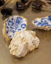Set of three handmade oyster shell trinket dishes with blue and white floral designs, featuring a decoupage technique and hand-painted gold edges, ideal for home decor or jewellery storage.