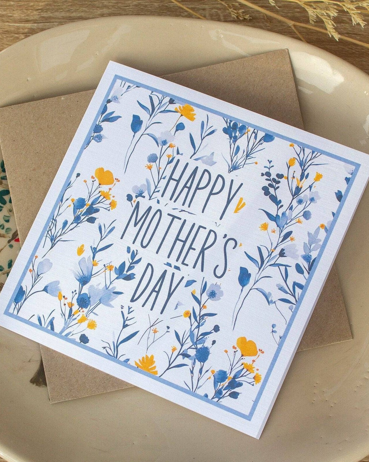 Square handmade Mother’s Day card featuring a vintage blue and yellow floral design with "Happy Mother’s Day" text in the centre. Packaged in a biodegradable cello wrap with a Kraft envelope.
