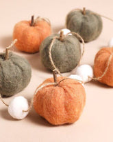 Decorative string of felt pumpkins and apples on a beige background