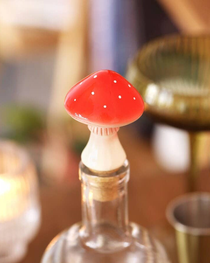 Bottle stopper shaped like a red mushroom on a blurred bar background