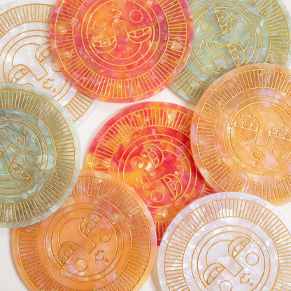 Set of round handmade coasters in various colours acetate with engraved, gold-filled Sol face detail. Suitable for indoor or outdoor use. Perfect for home décor or barware.