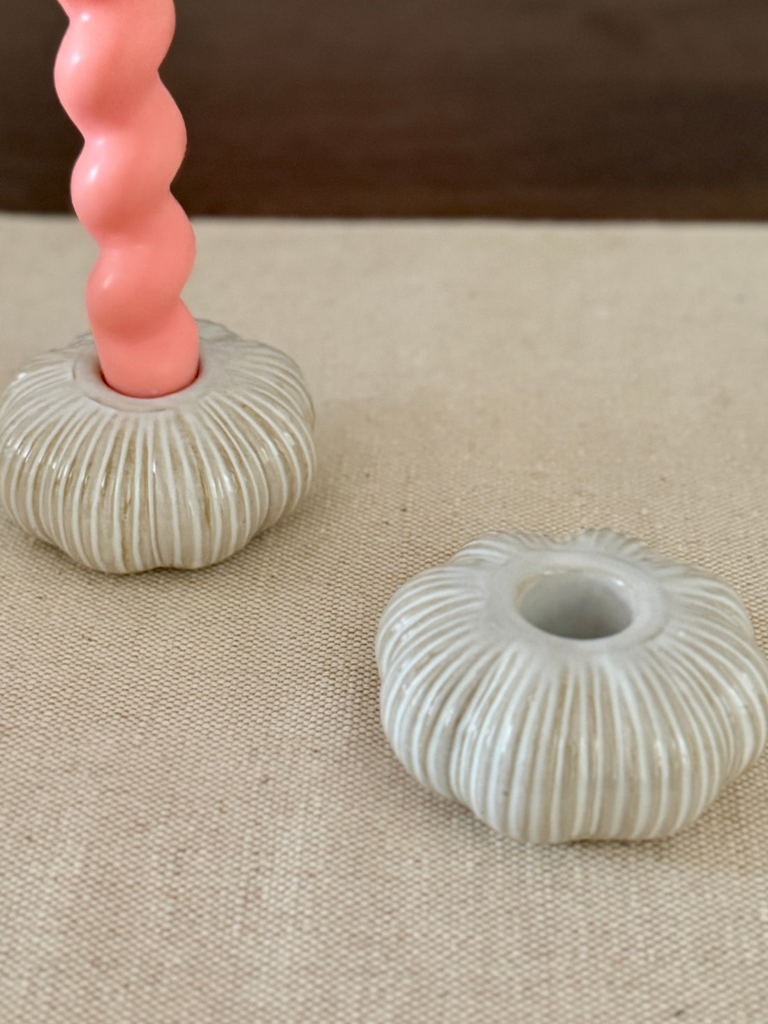 Decorative candle holders with a pink textured candle on a beige surface