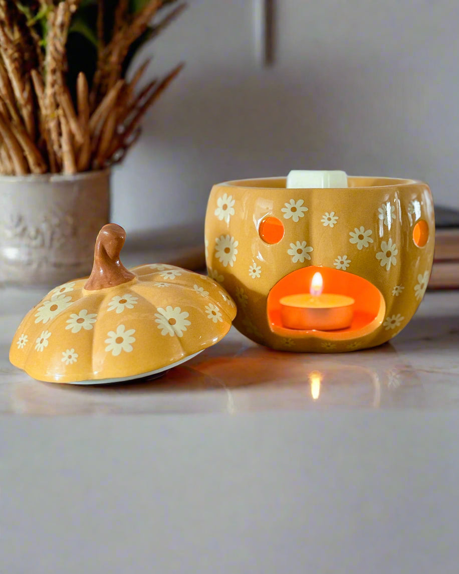 Yellow ceramic container with a lid and a small candle inside on a wooden surface.