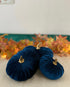 Three navy blue velvet pumpkins with gold stems on a neutral surface with a decorative background.