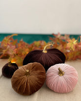 Decorative pumpkins in brown and pink on a table with a floral background