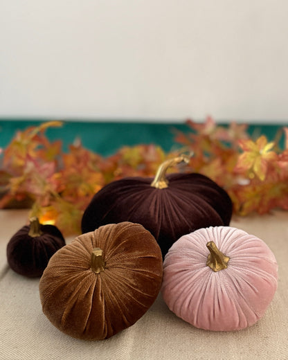 Decorative pumpkins in brown and pink on a table with a floral background