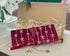 Red jewelry pouch with white patterns on a beige surface, with a gold ring and necklace displayed.