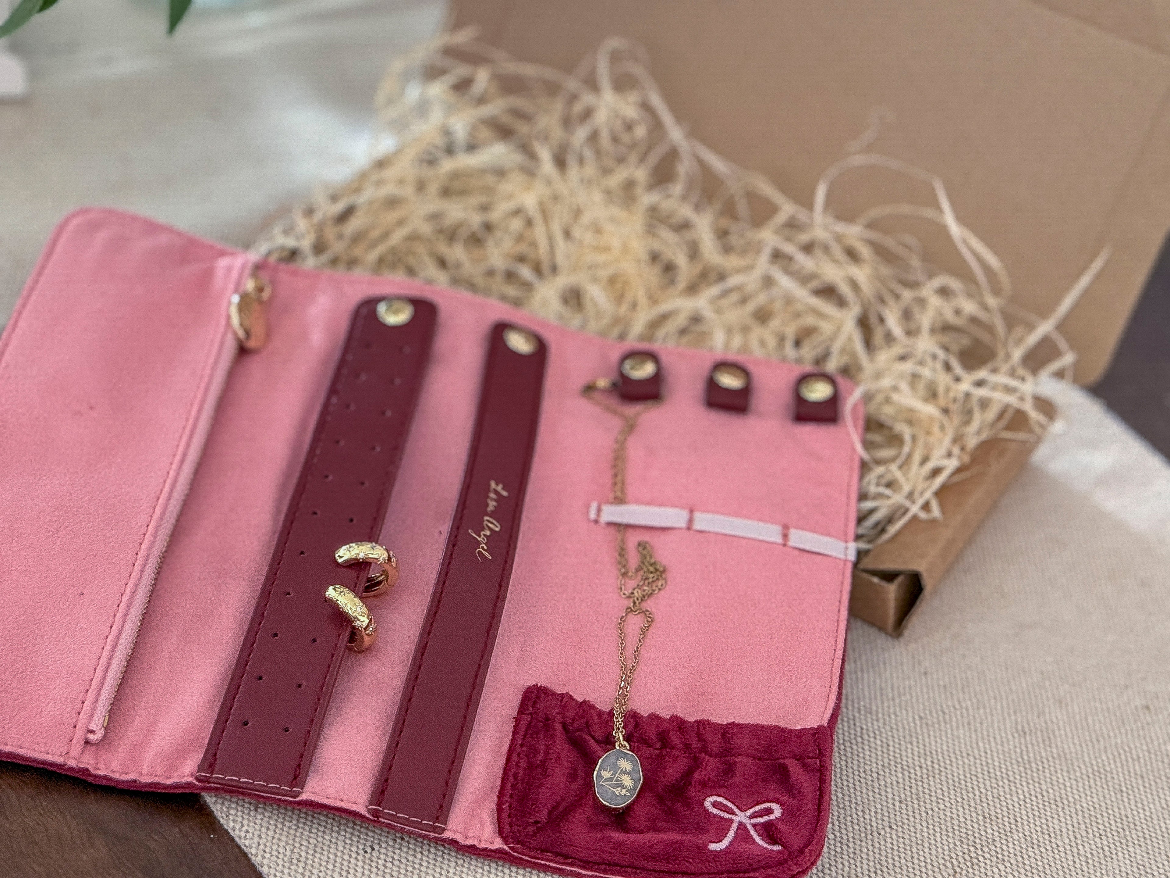 Pink jewelry organizer with necklaces and earrings on a neutral background