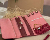 Pink jewelry organizer with jewelry on a textured surface