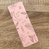 Boho-themed waterproof bookmark with "Just One More Chapter" text, featuring illustrations of moons, leaves, and abstract shapes in pink and brown tones. Made from recycled card with a velvet lamination.