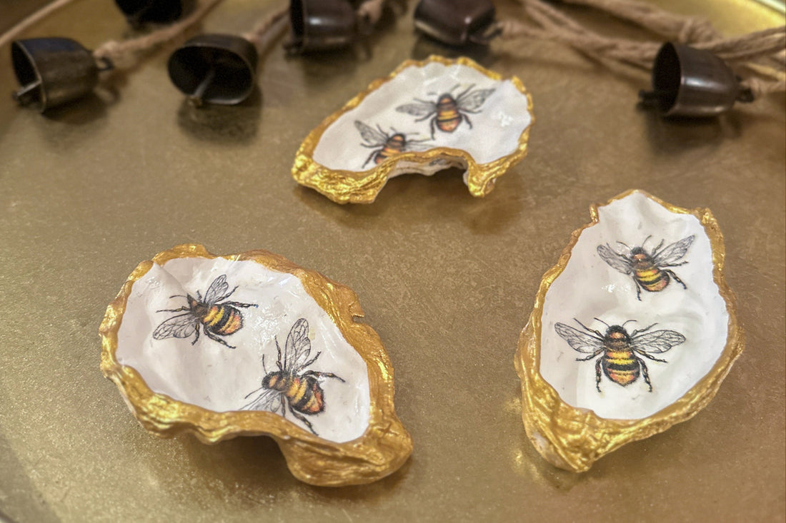 Handmade oyster shells trinket trays featuring two bumble bees, crafted using a meticulous decoupage technique with hand-painted gold edges, perfect for spring jewellery storage or home decor.