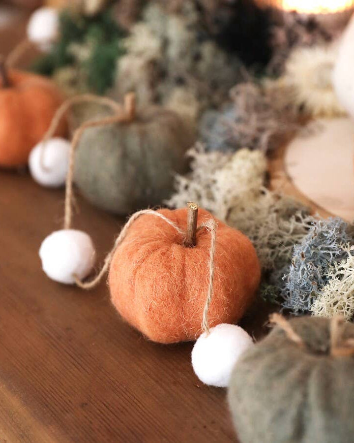 Decorative arrangement of pumpkins and white balls on a wooden surface with a blurred background.