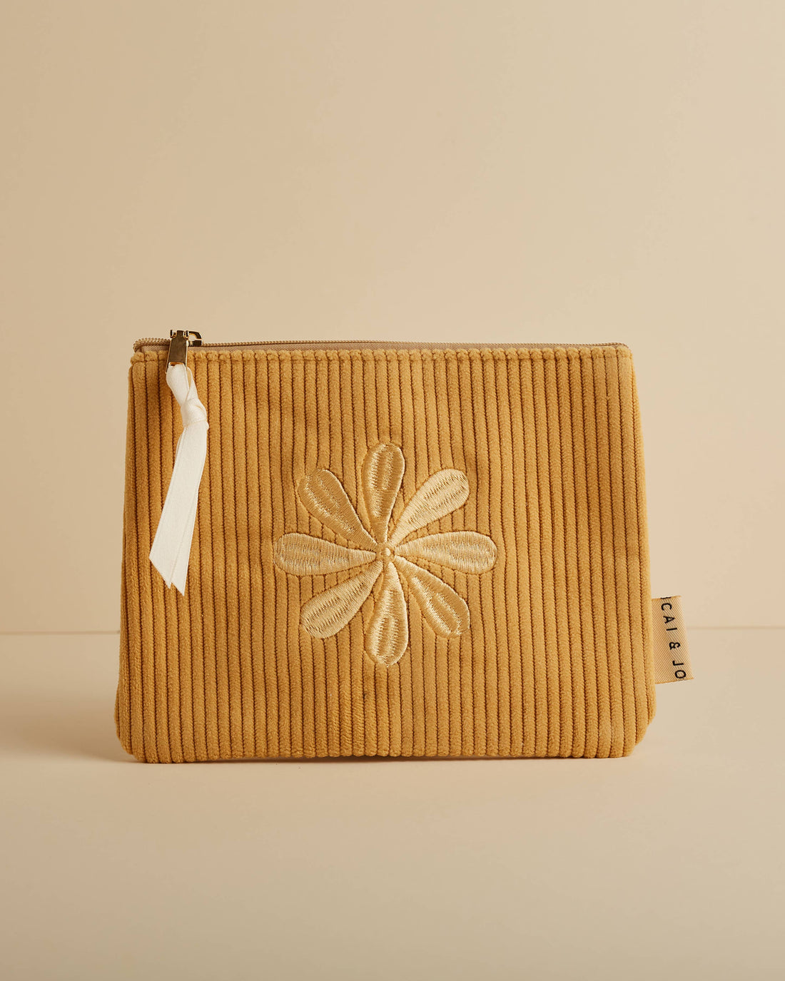Marigold corduroy pouch with a zip closure and embroidered flower design. Fully lined and perfect for storing makeup, toiletries, or travel essentials.