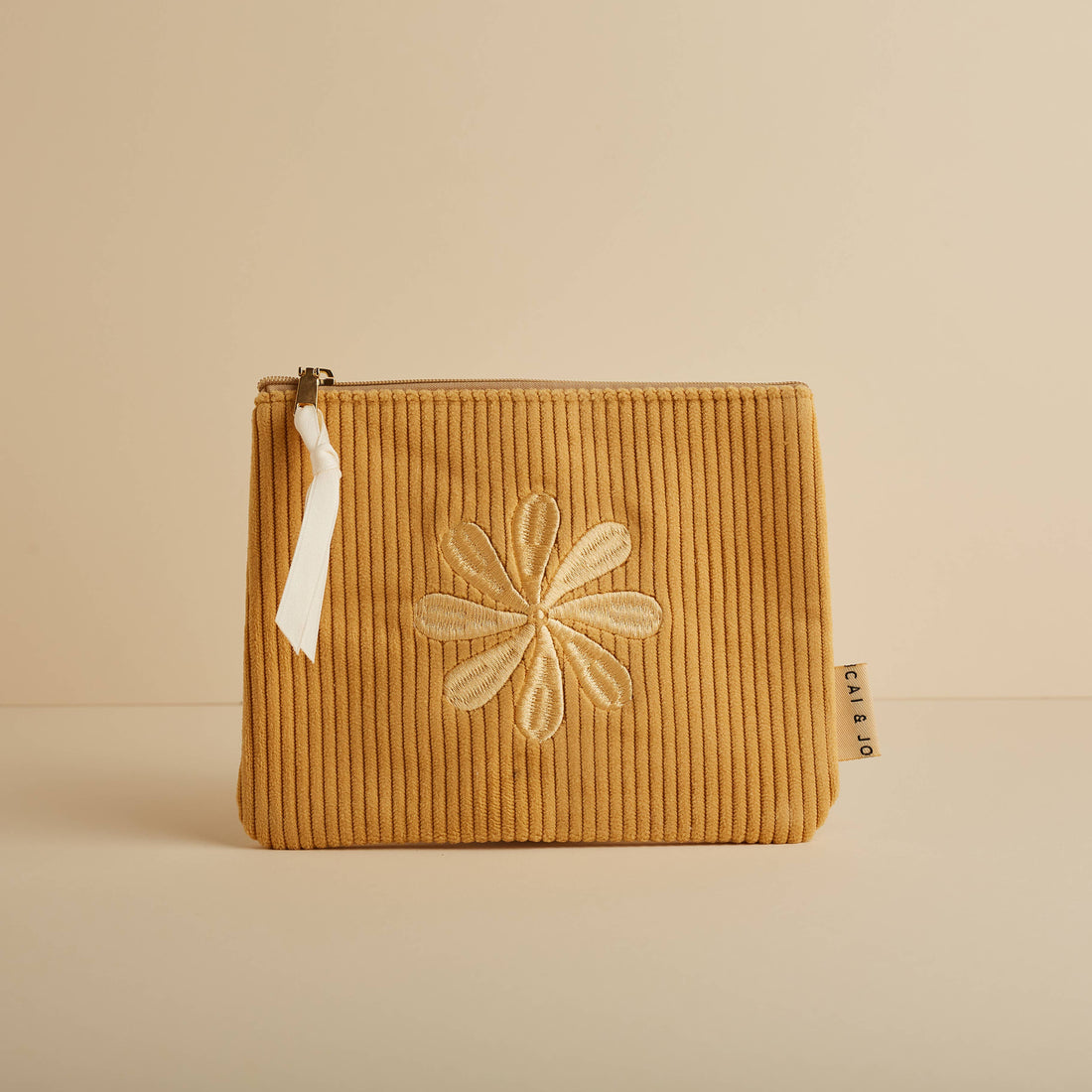 Marigold corduroy pouch with a zip closure and embroidered flower design. Fully lined and perfect for storing makeup, toiletries, or travel essentials.