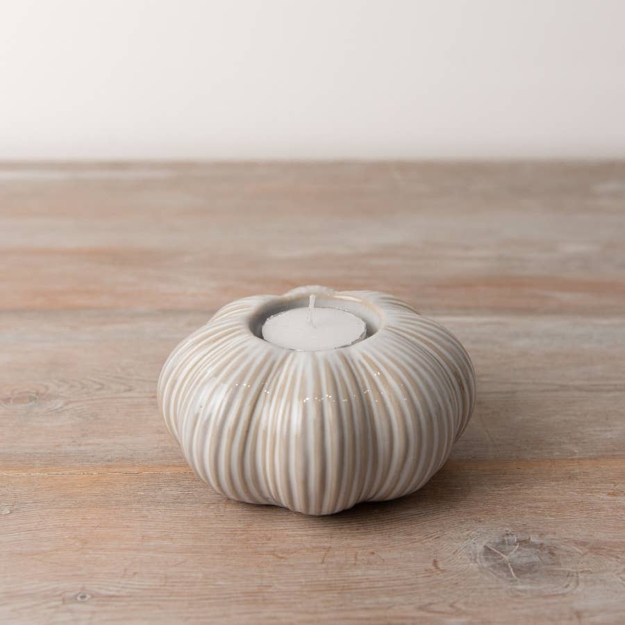 Set of two ceramic pumpkin tea light holders featuring intricate ribbing and a warm cream colour. Ideal for autumn décor.