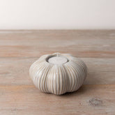 Set of two ceramic pumpkin tea light holders featuring intricate ribbing and a warm cream colour. Ideal for autumn décor.