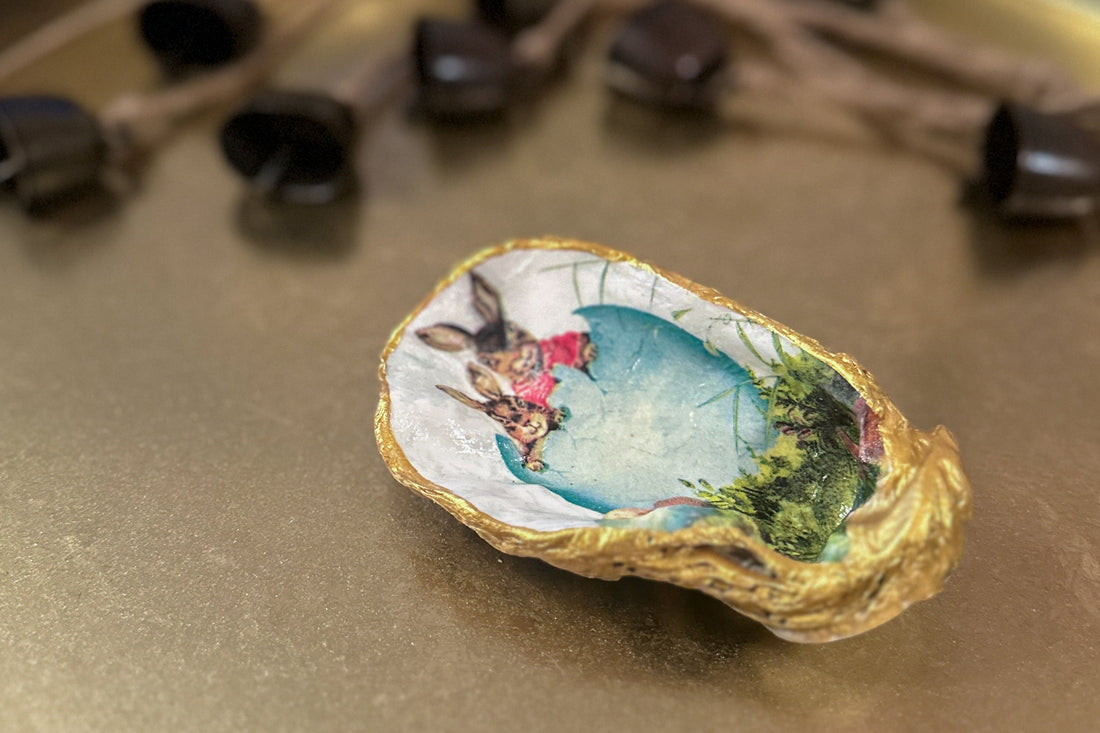 Handmade oyster shell trinket dish featuring an Easter bunny and open egg shell illustration, crafted with a decoupage technique and hand-painted gold edges, perfect for Easter or springtime gifts.