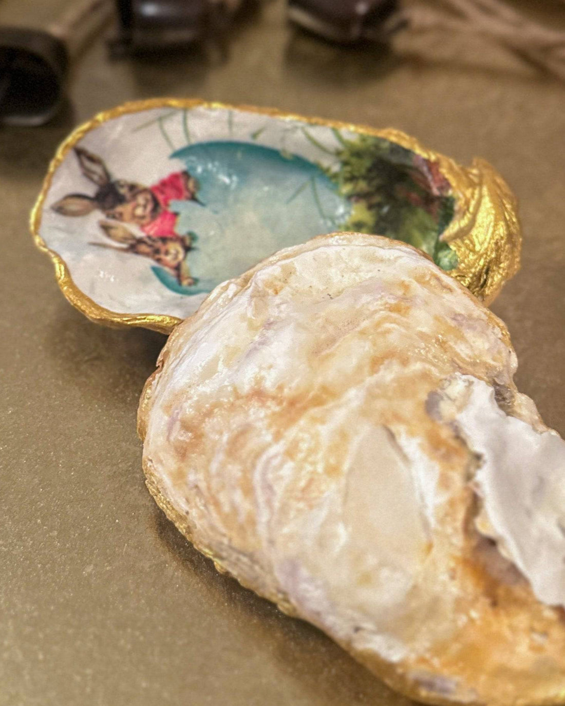 Handmade oyster shell trinket dish featuring an Easter bunny and open egg shell illustration, crafted with a decoupage technique and hand-painted gold edges, perfect for Easter or springtime gifts.