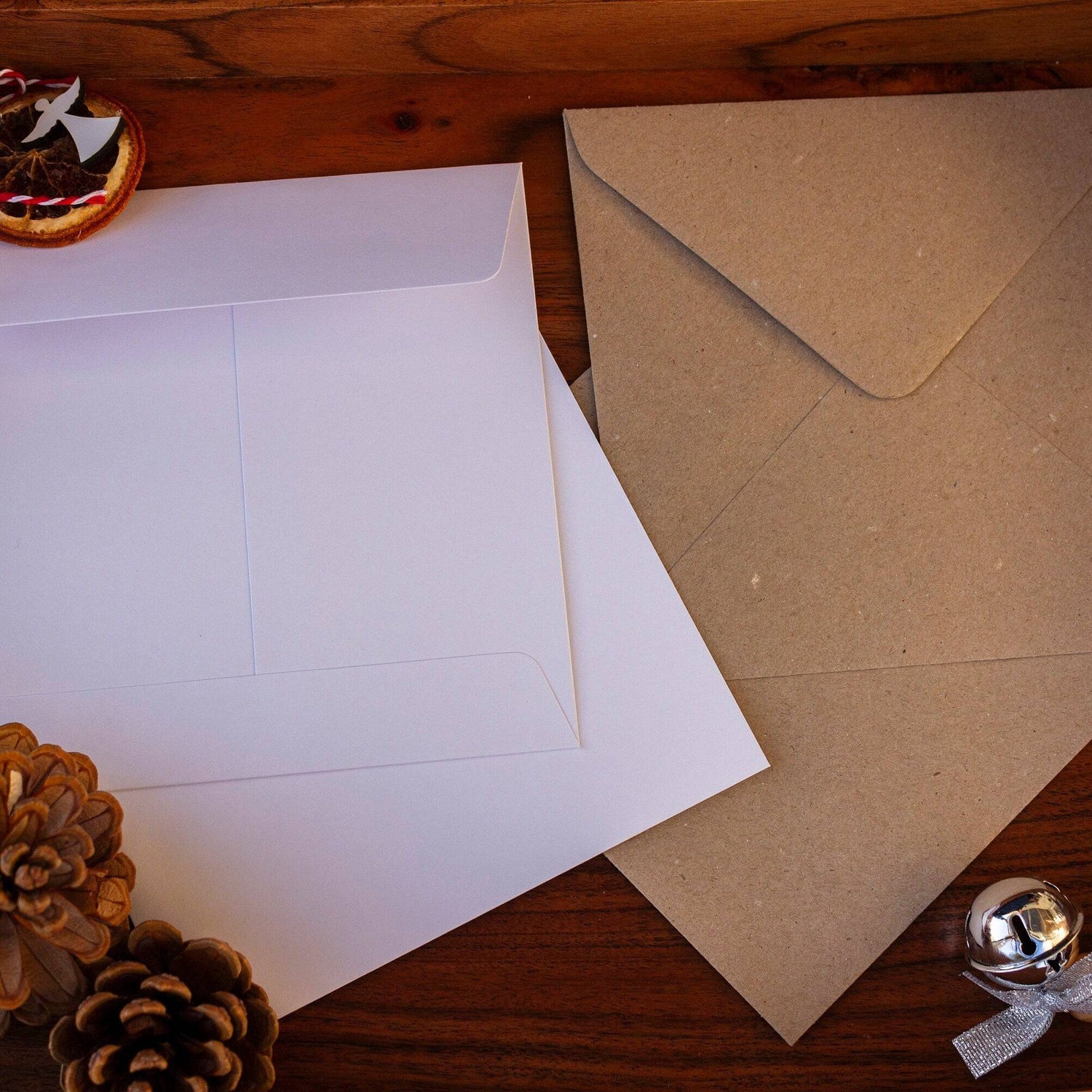 Envelope options for the Square Christmas card with white snowy trees, hanging gold and white baubles, and &quot;Merry Christmas&quot; written in gold. Made from recyclable luxury textured paper with eco-friendly packaging. Kraft or white.