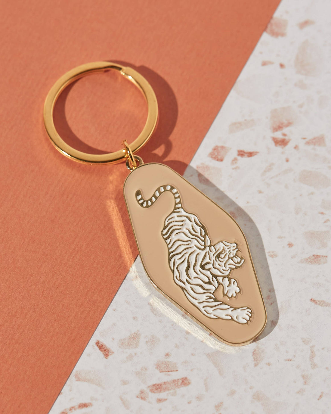 Soft enamel keychain featuring a pale peach background with a tiger design and gold highlights. Includes a matching gold ring.