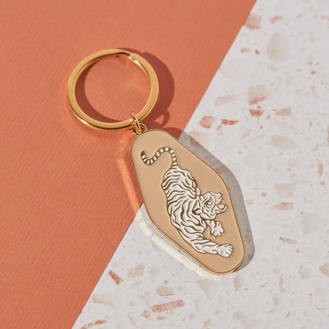 Soft enamel keychain featuring a pale peach background with a tiger design and gold highlights. Includes a matching gold ring.